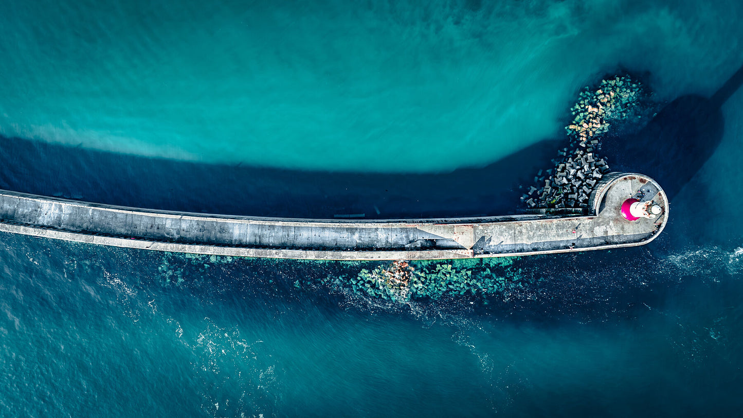 Aerial view of Newhaven lighthouse and wave breakers in clear, blue waters. Print or framed photography art.