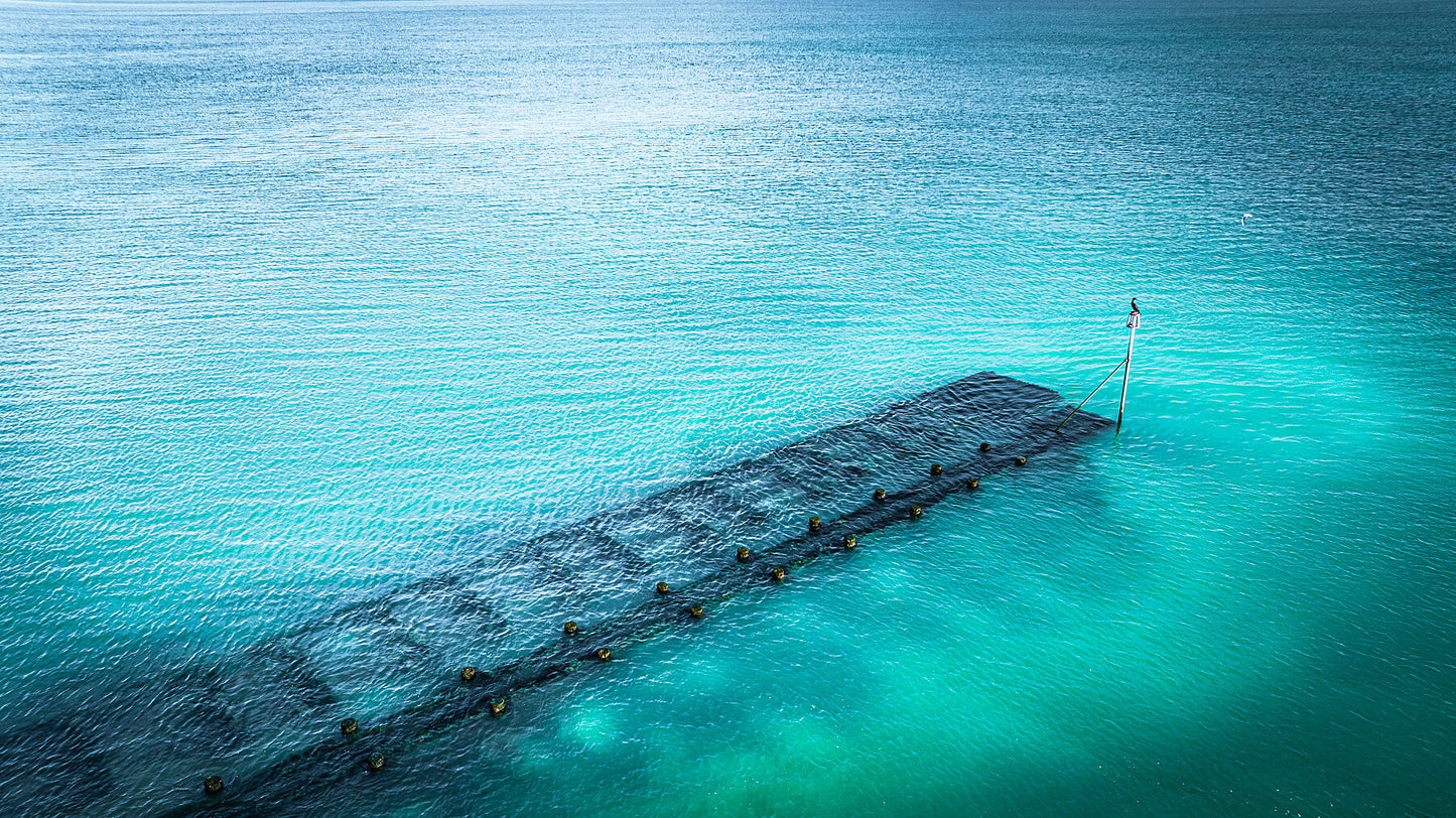 Blue waters of Lancing beach with remains of some wooden structure. Print or framed photography art.