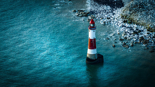 Lighthouse in blue waters of Eastbourne just off the cliff of Beachy Head, Eastbourne, East Sussex, UK