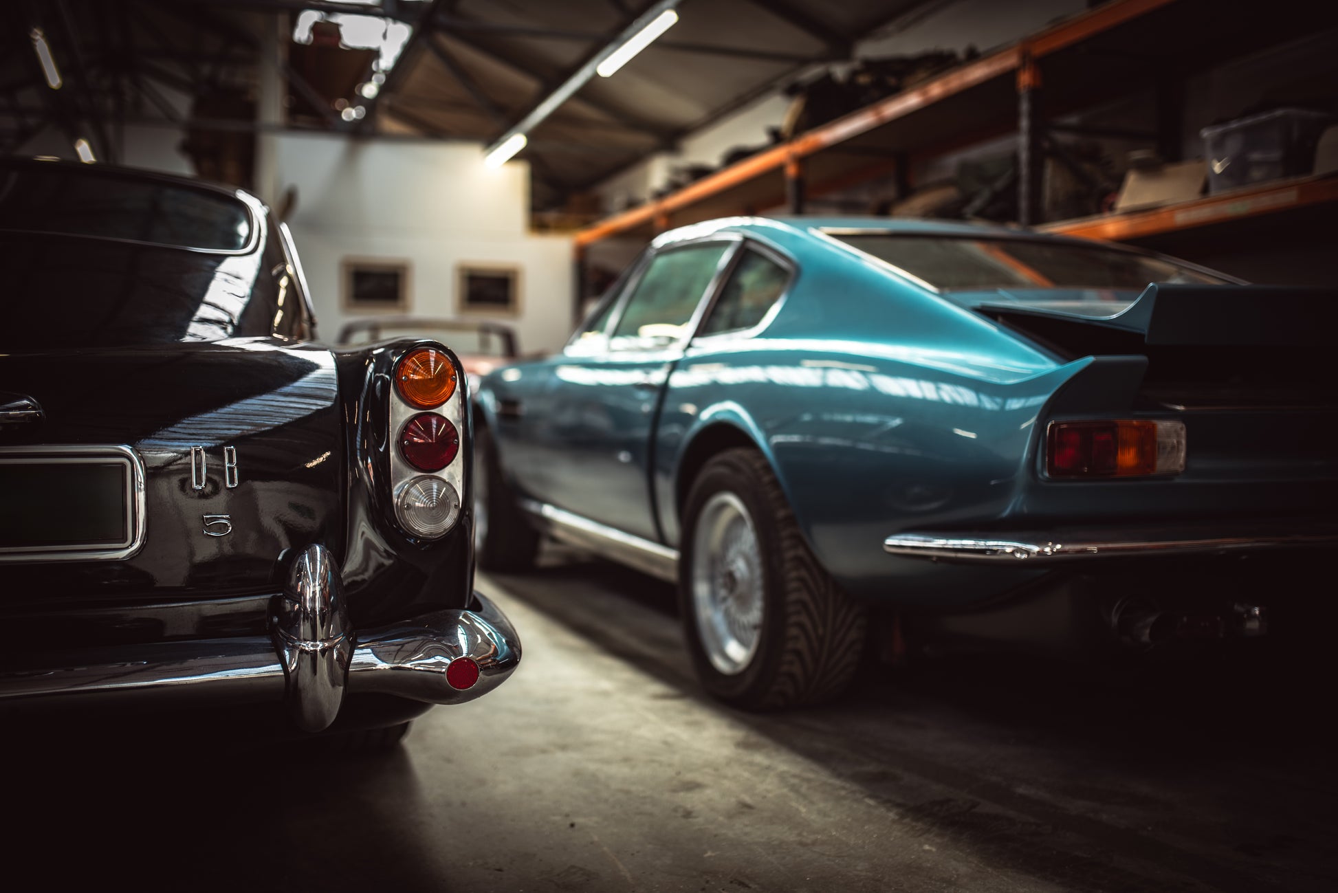 Pair of British classic Aston Martins DB5 and V8 parked up in a garage. Automotive Photography, classic car, vintage vehicle, car photography. Photo print, wall decor.